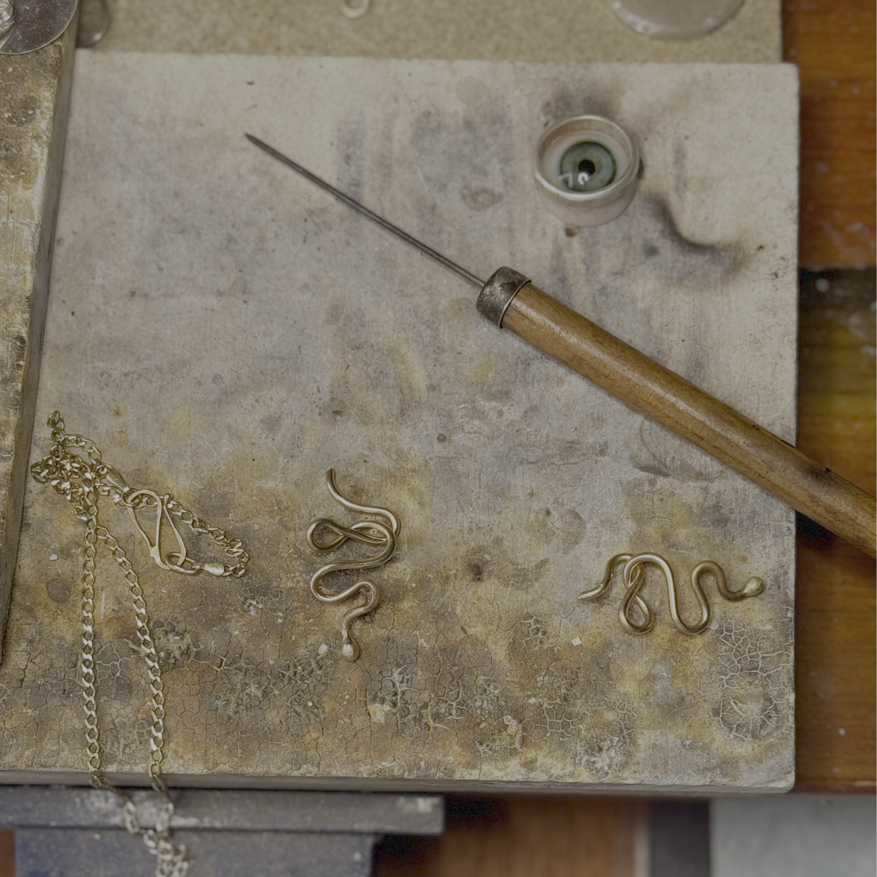 Gold jewelry pieces on a workbench with tools